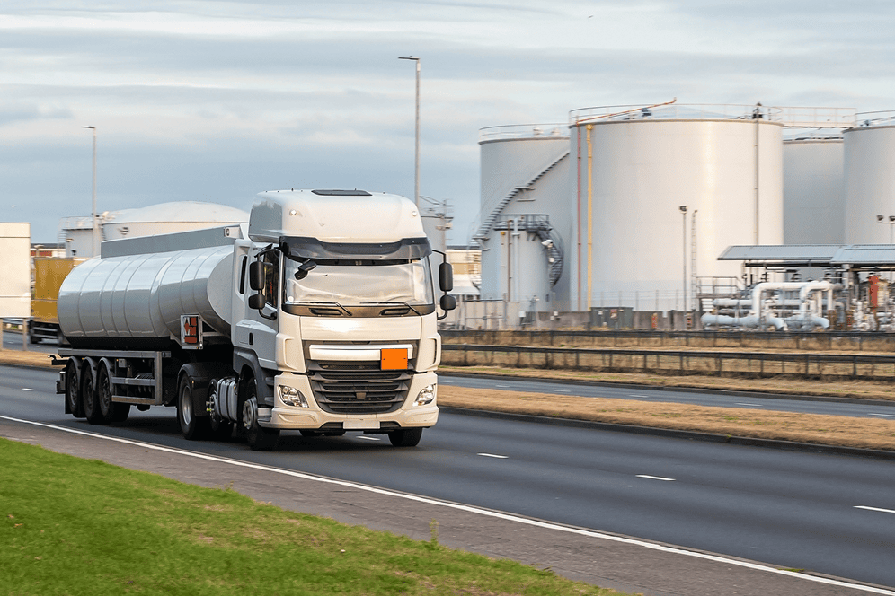 Tanker truck driving past industrial storage tanks